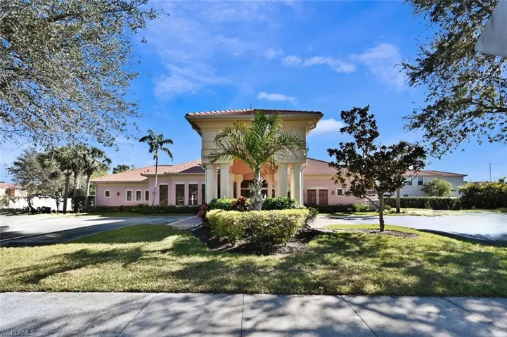 View of front facade with a front yard, a tile roof, and stucco siding