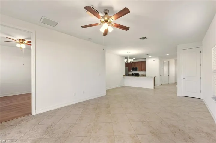 Unfurnished living room with a ceiling fan, a chandelier, and light tile patterned flooring
