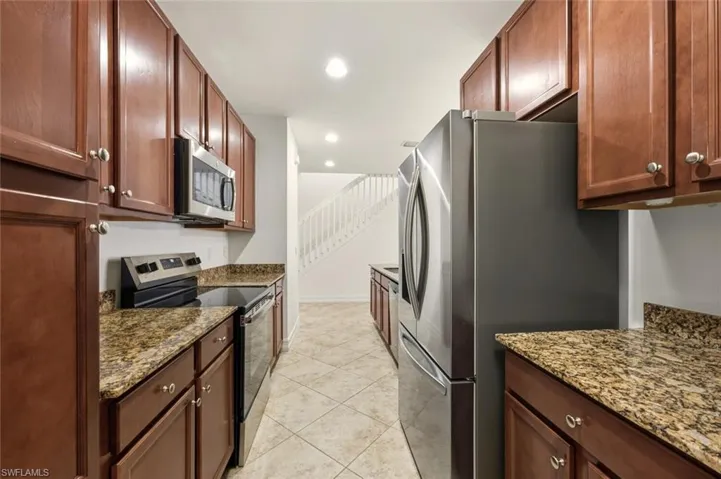 Kitchen with stainless steel appliances, light stone countertops, recessed lighting, and light tile patterned floors