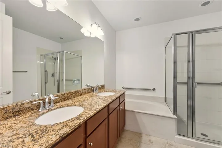 Full bathroom with a stall shower, double vanity, and a bath
