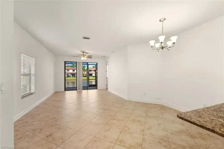 Spare room featuring a chandelier, a ceiling fan, and light tile patterned flooring