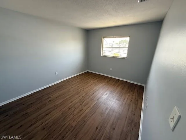 Empty room featuring dark wood finished floors and a textured ceiling