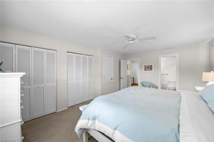 Carpeted bedroom featuring two closets, a ceiling fan, and ensuite bathroom