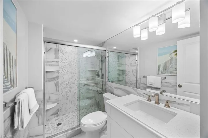 Bathroom featuring a marble finish shower, vanity, and recessed lighting
