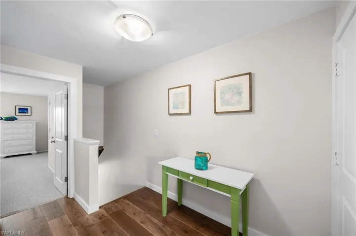 Hallway featuring an upstairs landing and dark wood-style flooring