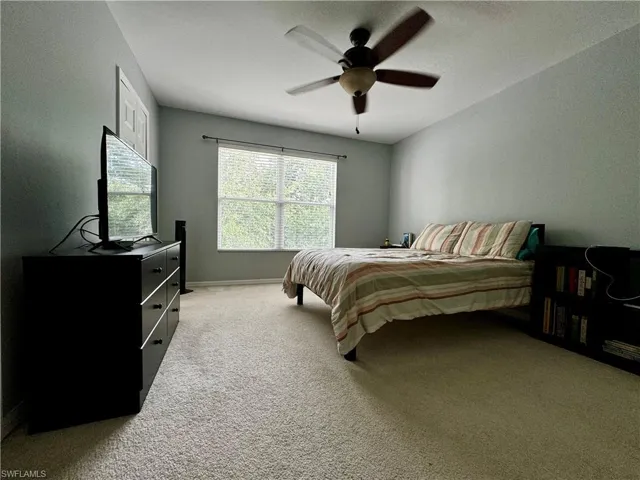 Carpeted bedroom featuring ceiling fan