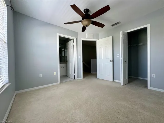 Unfurnished bedroom with light carpet, ensuite bath, ceiling fan, and a closet