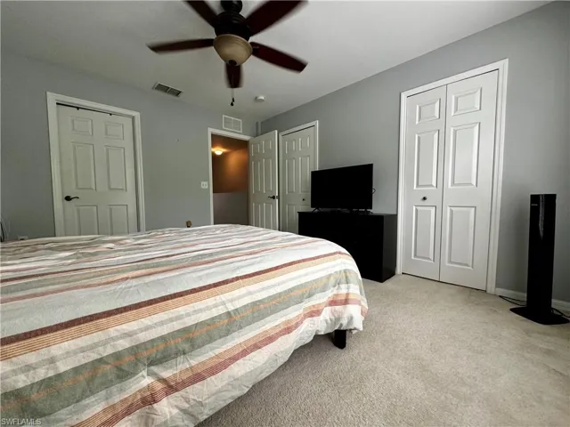 Bedroom with multiple closets, carpet flooring, and ceiling fan