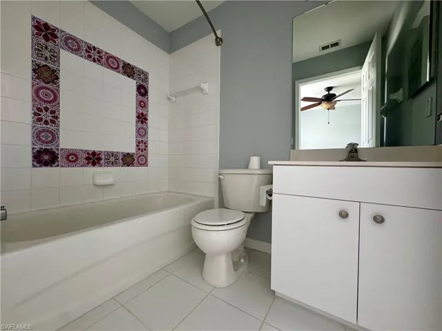 Full bathroom with ceiling fan, tiled shower / bath, vanity, tile patterned floors, and toilet
