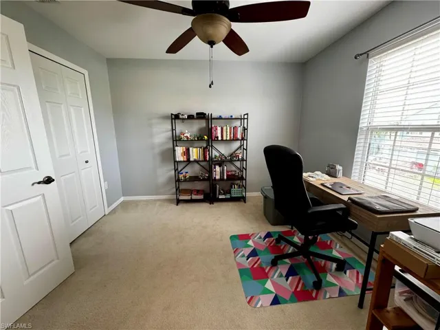 Carpeted office space featuring ceiling fan and plenty of natural light