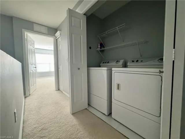 Laundry area featuring light carpet and separate washer and dryer