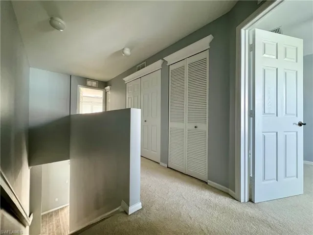 Hallway featuring light colored carpet