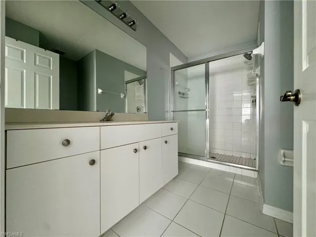 Bathroom featuring tile patterned flooring, walk in shower, and vanity