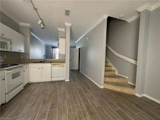 Kitchen featuring sink, white appliances, track lighting, white cabinetry, and dark hardwood / wood-style floors