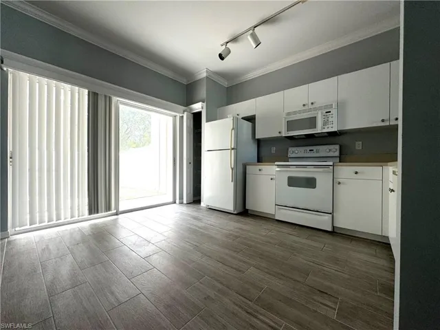 Kitchen featuring rail lighting, white cabinets, white appliances, dark hardwood / wood-style flooring, and ornamental molding