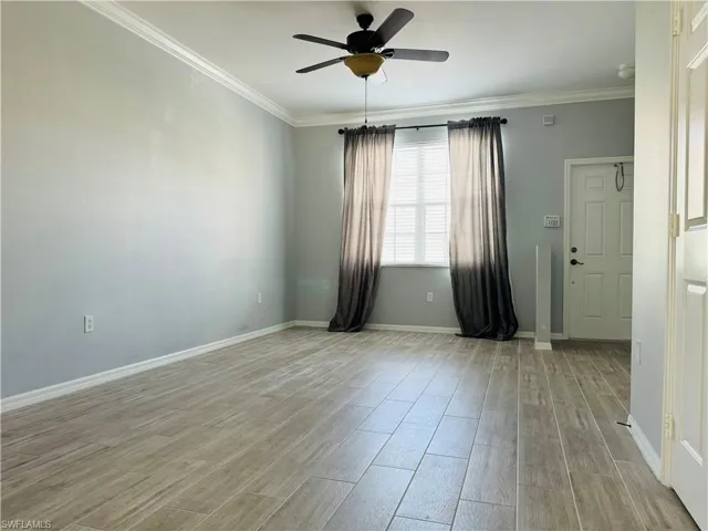 Spare room featuring light wood-type flooring, ceiling fan, and crown molding