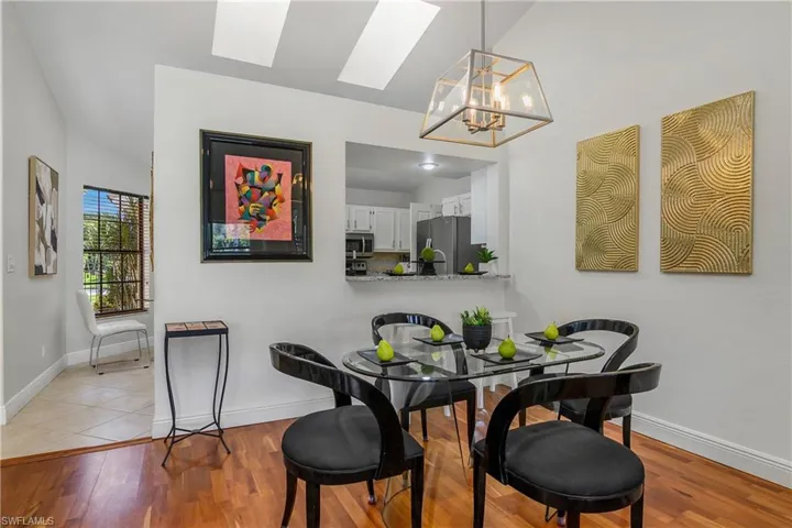 Dining space featuring a skylight, baseboards, light wood-style floors, and vaulted ceiling