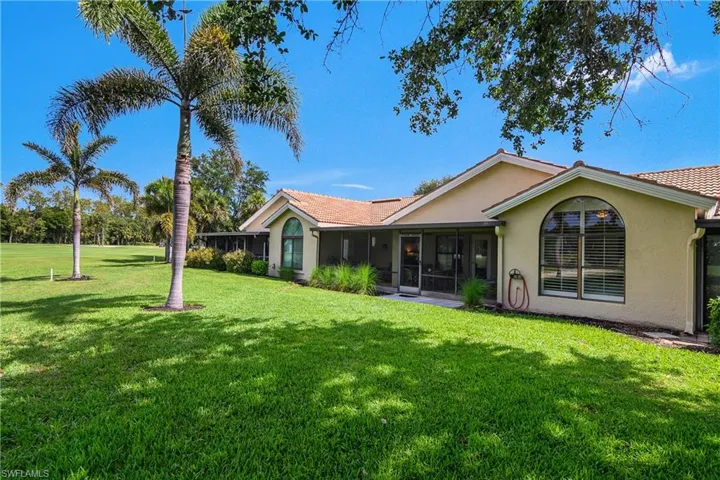 Rear view of property with a sunroom, a yard, and stucco siding
