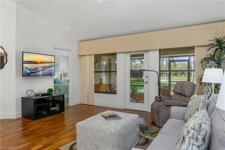 Living area featuring wood finished floors, lofted ceiling, french doors, and baseboards