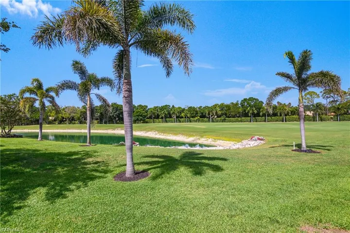 View of property's community featuring a water view, a yard, view of scattered trees, and golf course view
