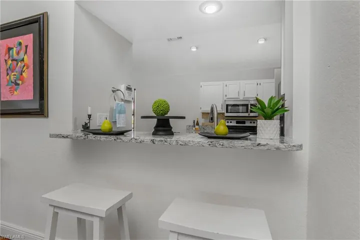 Kitchen with stainless steel appliances, white cabinets, a peninsula, and light countertops