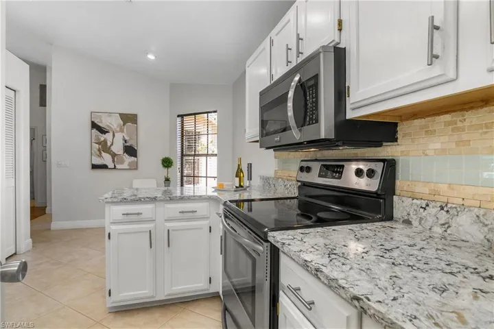 Kitchen featuring appliances with stainless steel finishes, a peninsula, white cabinetry, and tasteful backsplash
