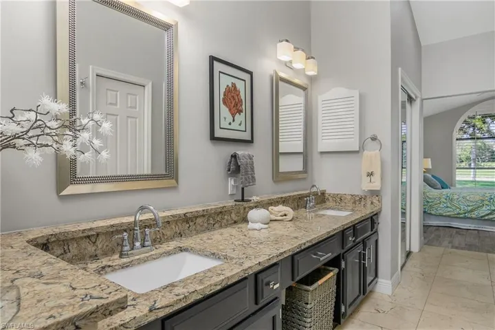Ensuite bathroom featuring marble look tile flooring, double vanity, and baseboards