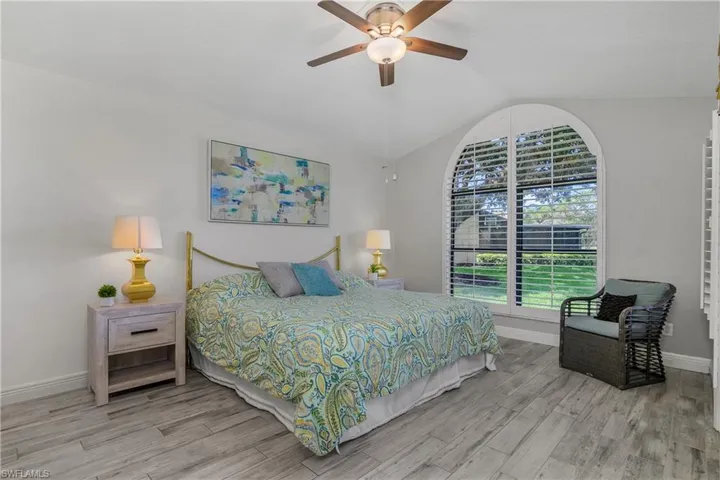 Bedroom with wood finished floors, lofted ceiling, baseboards, and ceiling fan