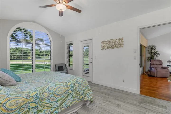 Bedroom with vaulted ceiling, access to exterior, light wood finished floors, a ceiling fan, and baseboards