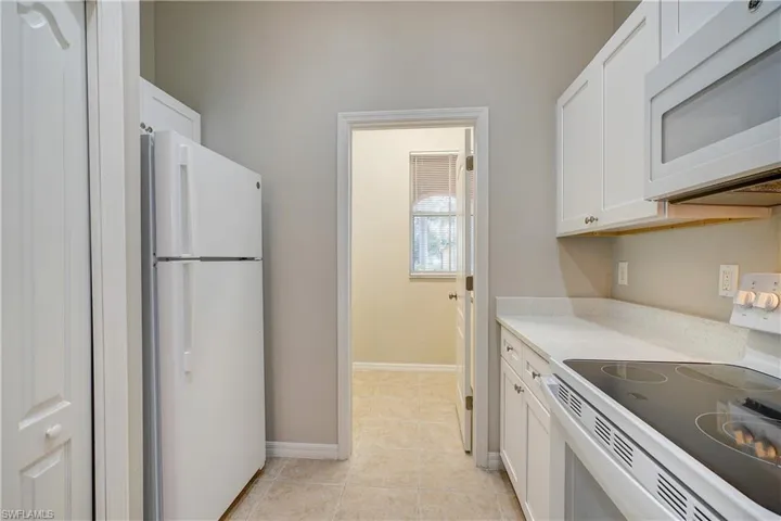Kitchen featuring light tile flooring, white cabinets, and white appliances