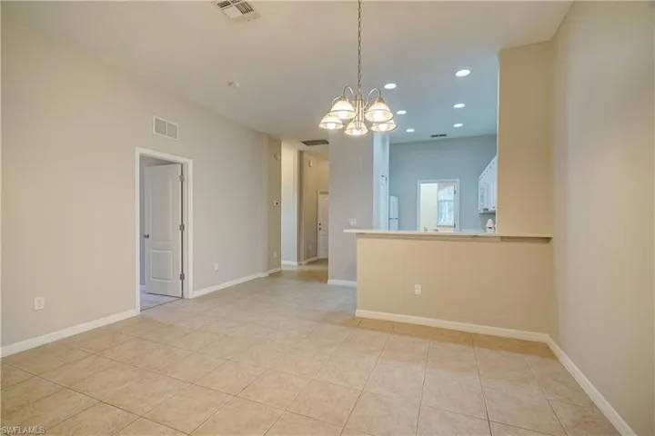 Unfurnished room featuring a chandelier and light tile floors