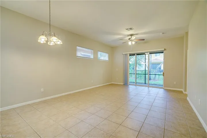 Empty room featuring ceiling fan with notable chandelier and light tile flooring