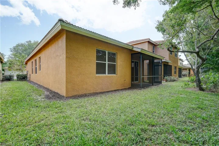 Rear view of house featuring a yard and a sunroom