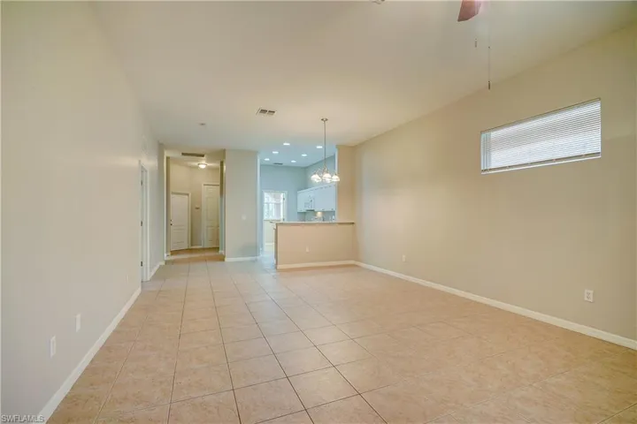 Unfurnished living room featuring a healthy amount of sunlight, light tile floors, and ceiling fan with notable chandelier