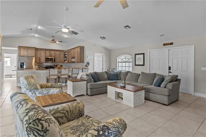 Living room with light tile patterned floors, ceiling fan, recessed lighting, and high vaulted ceiling