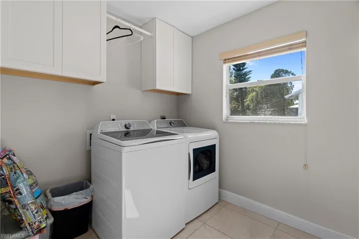 Laundry room with cabinet space, light tile patterned floors, and independent washer and dryer