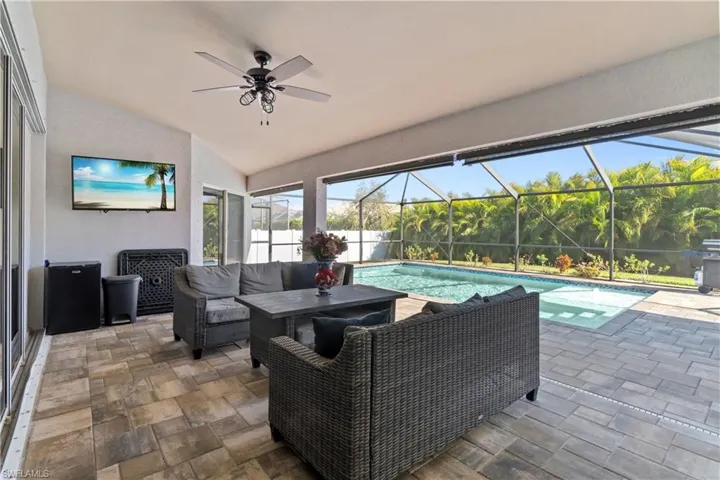 View of patio / terrace featuring outdoor lounge area, glass enclosure, a sunroom, a ceiling fan, and an outdoor pool