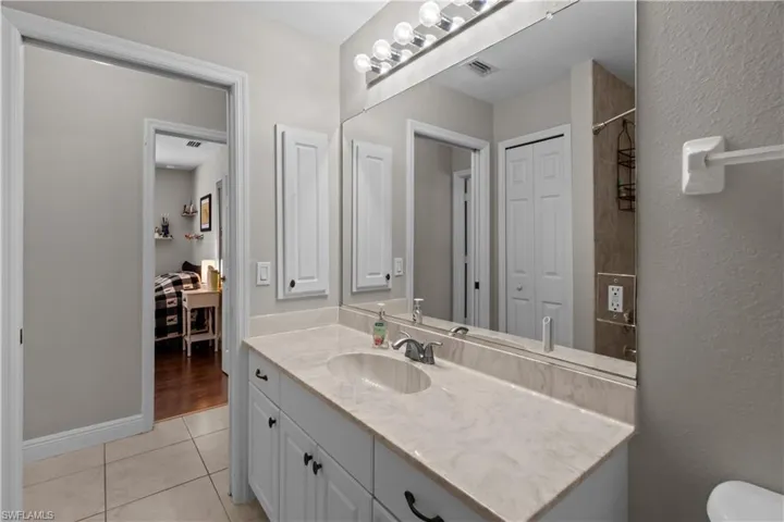 Full bath featuring vanity, light tile patterned floors, a shower, and a textured wall