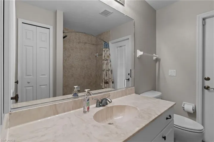 Bathroom featuring a closet, vanity, and tiled shower