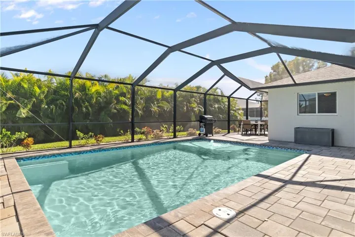Swimming pool with grilling area, glass enclosure, a sunroom, a patio, and outdoor dining space