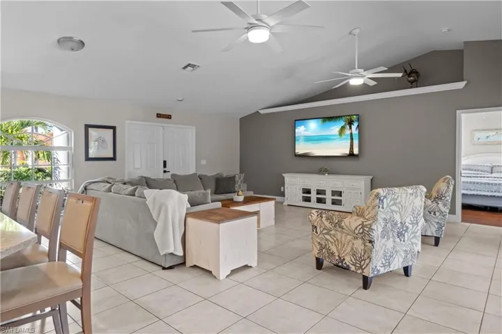 Living room featuring vaulted ceiling, light tile patterned flooring, and a ceiling fan