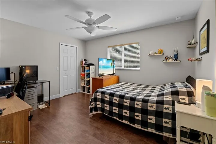 Bedroom featuring an office area, dark wood-type flooring, a closet, and a ceiling fan