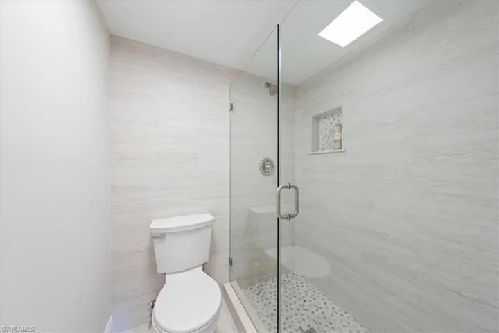 Bathroom featuring tile walls, toilet, and an enclosed shower
