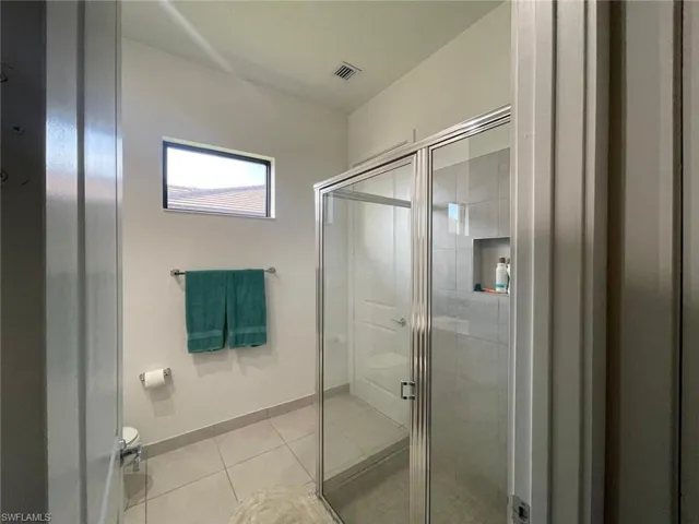 Full bath with a shower stall and light tile patterned floors