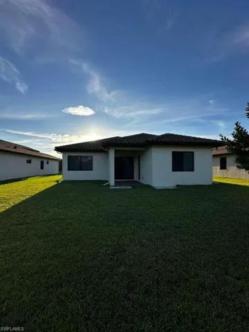 View of front facade featuring a front lawn, stucco siding, and a patio
