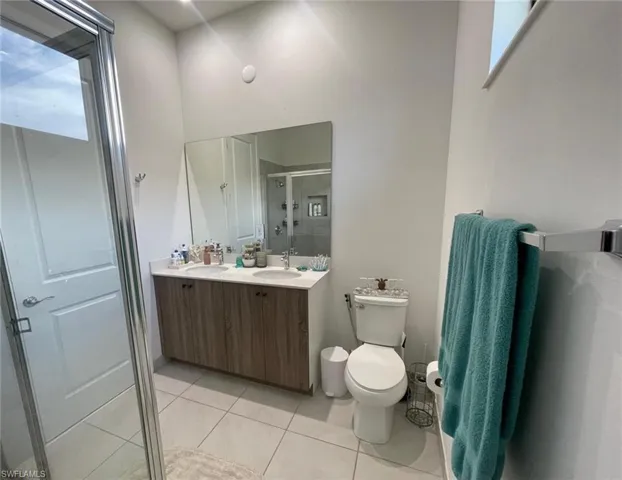 Bathroom featuring a stall shower, double vanity, and light tile patterned floors
