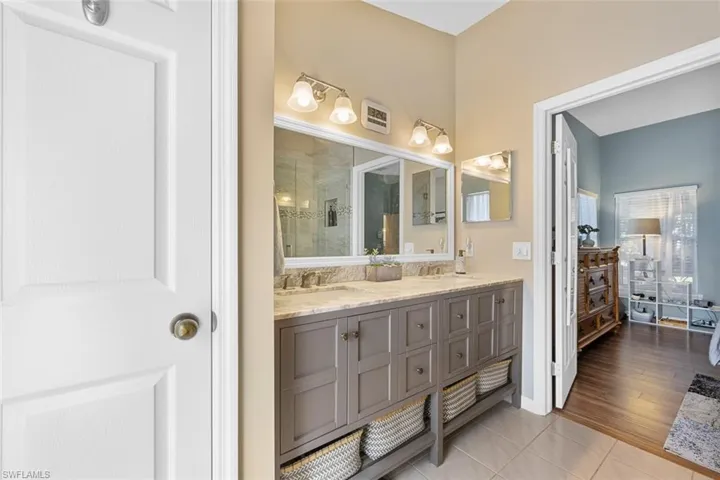 Newly remodeled primary bathroom with dual vanities, walk-in shower, & linen closet.