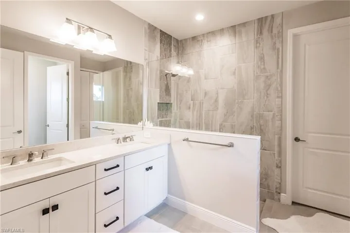 Bathroom with a walk in shower, double vanity, and light tile patterned floors