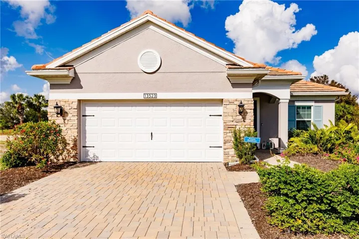 View of front of home featuring stone siding, decorative driveway, and stucco siding