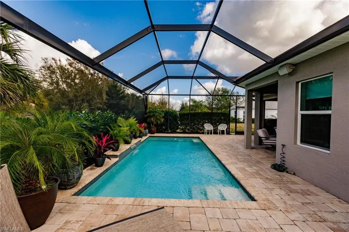 Outdoor pool with a patio, a sunroom, and glass enclosure